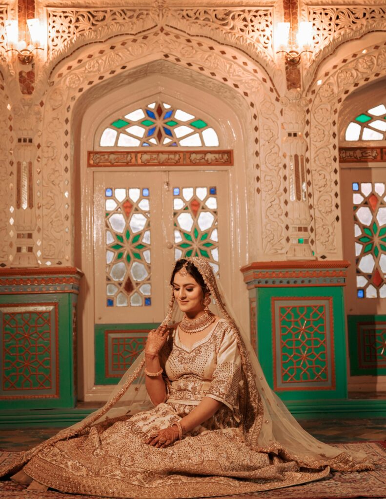 A beautiful bride in ornate traditional dress sits gracefully in a richly decorated interior in Srinagar.